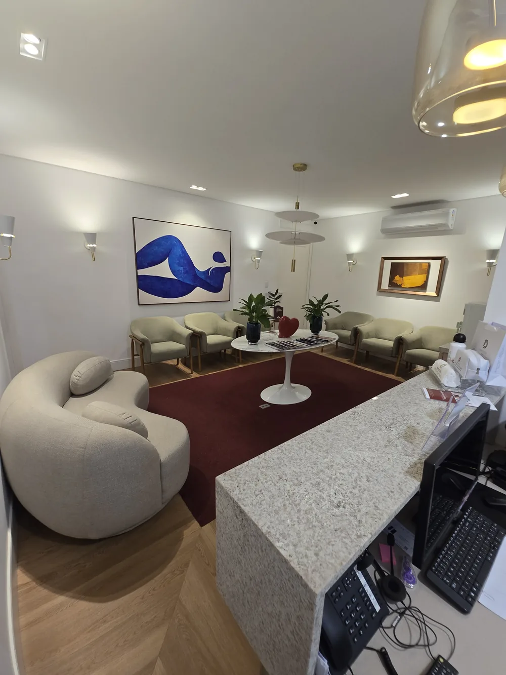 Balcão de recepção e atendimento do consultório, com sala de espera ao fundo