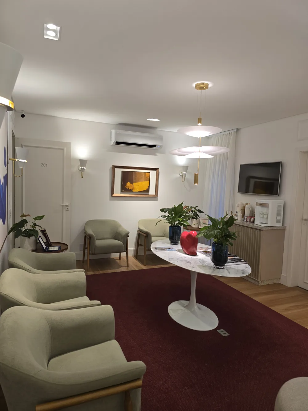 Sala de espera e circulação do consultório, com poltronas confortáveis e mesa de centro