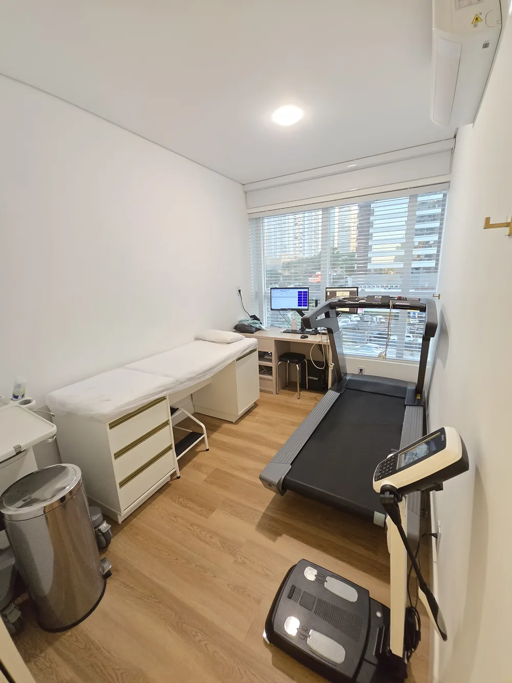 Sala de exames equipada com maca, esteira e balança de bioimpedância